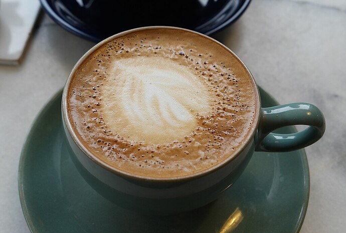 Cup of coffee with the distinctive leaf pattern of a flat white style coffee