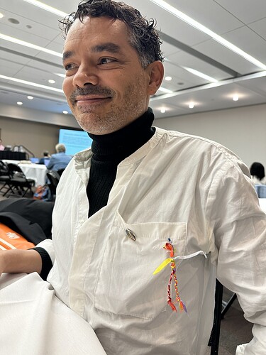 man with warm smile wearing colorful figure made of braided ribbons