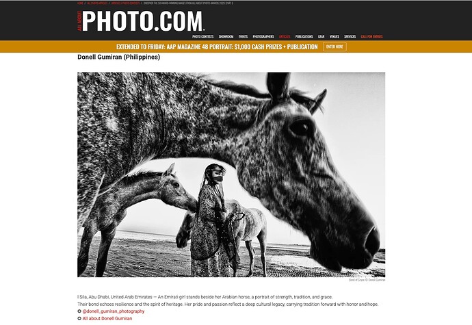 Black and white image of an Emirati girl standing beside Arabian horses on a beach.