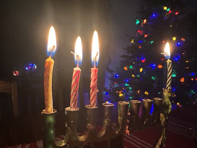 3rd night of Hanukkah candles in the menorah, in front of a lit Christmas Tree