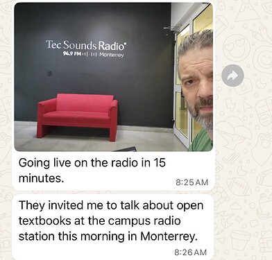 En la entrada de un estudio de radio, un sofá rojo frente a una pared gris que dice Tec Sounds Radio, a la derecha hay un hombre de cabello gris que mira muy inquisitivo.