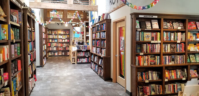 Book store with shelves loaded with books extending far back and hints of more around the corner