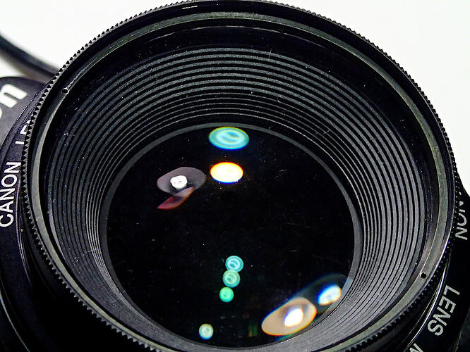 lens of an SLR camera with several colored lights reflected in the glass.