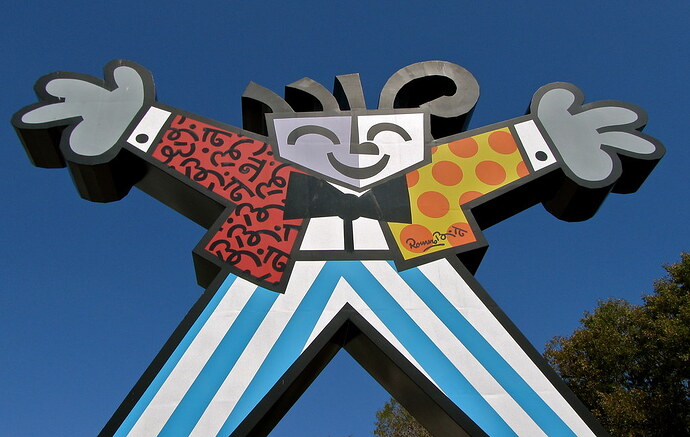 Colorful statue of figure with outstretched legs and hands offering a welcome